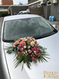 Autostuk met roze rozen op de motorkap van een trouwauto