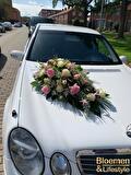 Autostuk met roze bloemen op een witte trouwauto